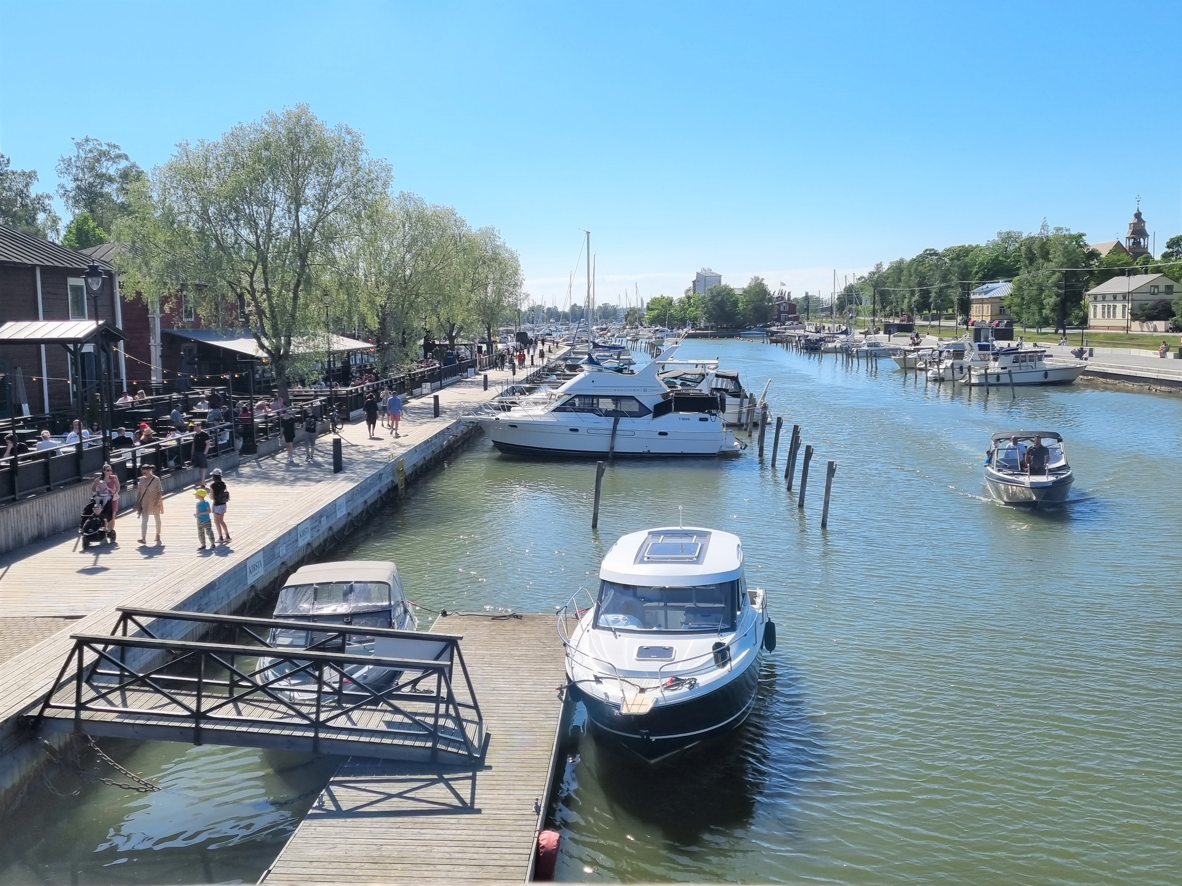 Kävelijöitä ja veneitä Kaupunginlahden rannalla